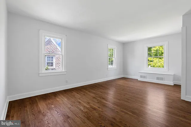 a view of an empty room with window and wooden floor