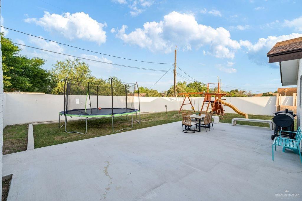 111 South Cox Street Rio Grande City, TX 78582 - Photo 17 of 27 Fenced backyard with a trampoline, a playground, and a patio area