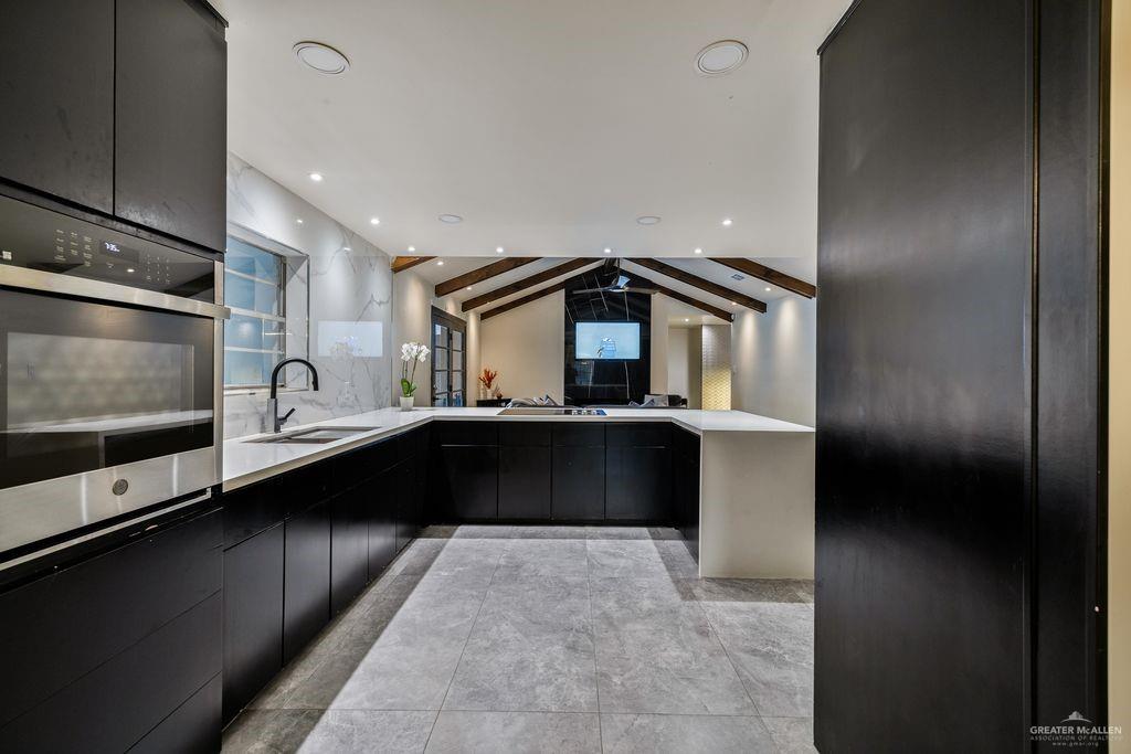 111 South Cox Street Rio Grande City, TX 78582 - Photo 27 of 27 Kitchen with dark cabinetry, a peninsula, open floor plan, light stone countertops, and modern cabinets