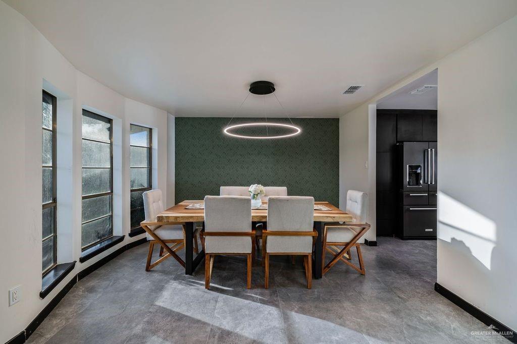 111 South Cox Street Rio Grande City, TX 78582 - Photo 7 of 27 Dining area featuring wallpapered walls, concrete floors, and an accent wall