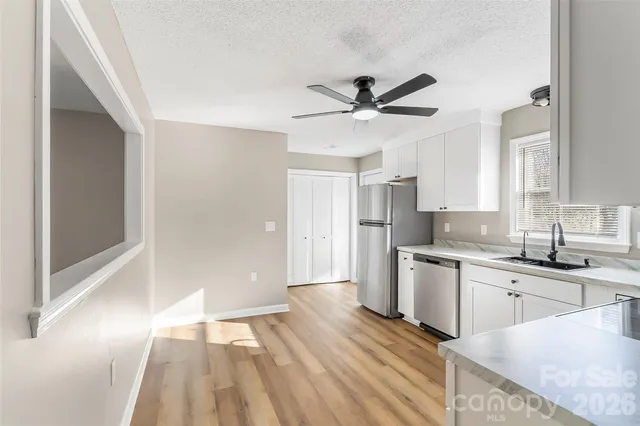 a view of a kitchen with a sink a refrigerator and wooden floor