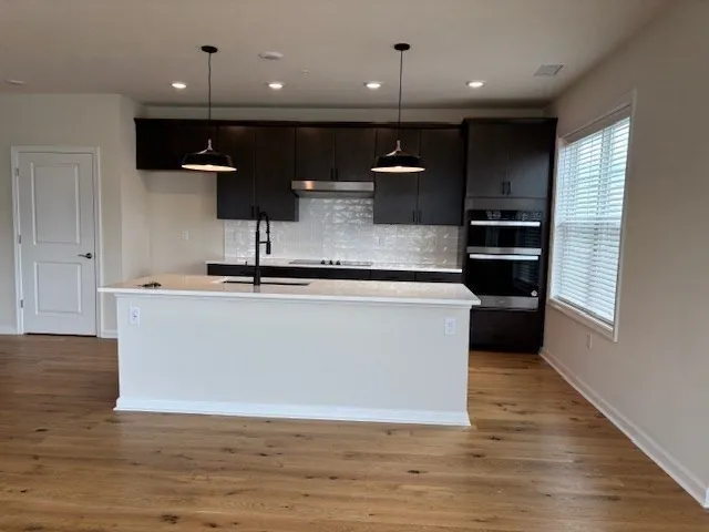 a view of kitchen with stainless steel appliances wooden floor large window and wooden floor