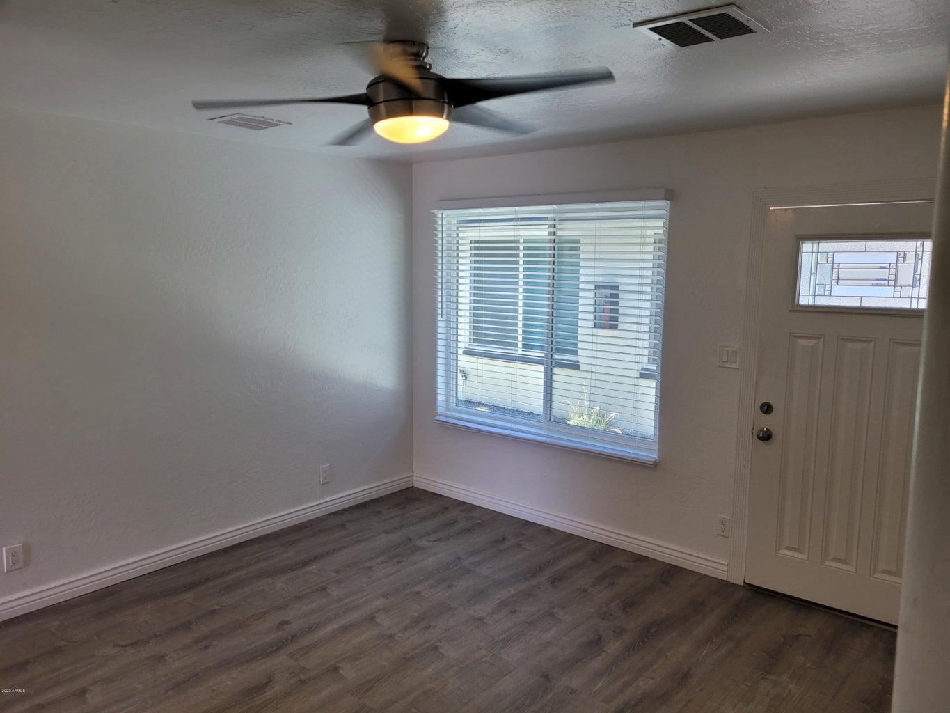 6713 East Cheery Lynn Road, Unit 2 Scottsdale, AZ 85251 - Photo 2 of 8 an empty room with wooden floor fan and windows