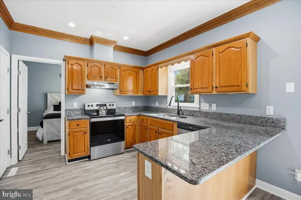 a kitchen with stainless steel appliances granite countertop a sink a stove and a wooden cabinets