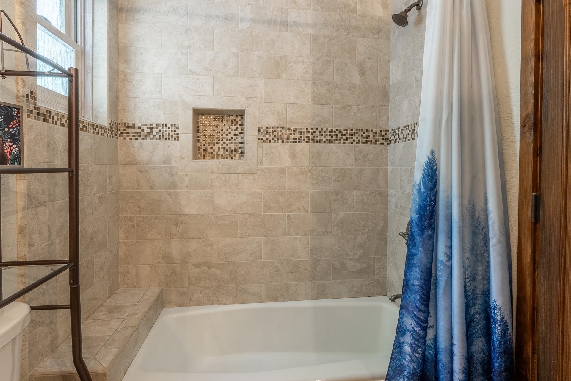139 Ridgecrest Drive Mammoth Lakes, CA 93546 - Photo 28 of 65 Bathtub and shower combination featuring neutral-toned tile surround with decorative mosaic accent