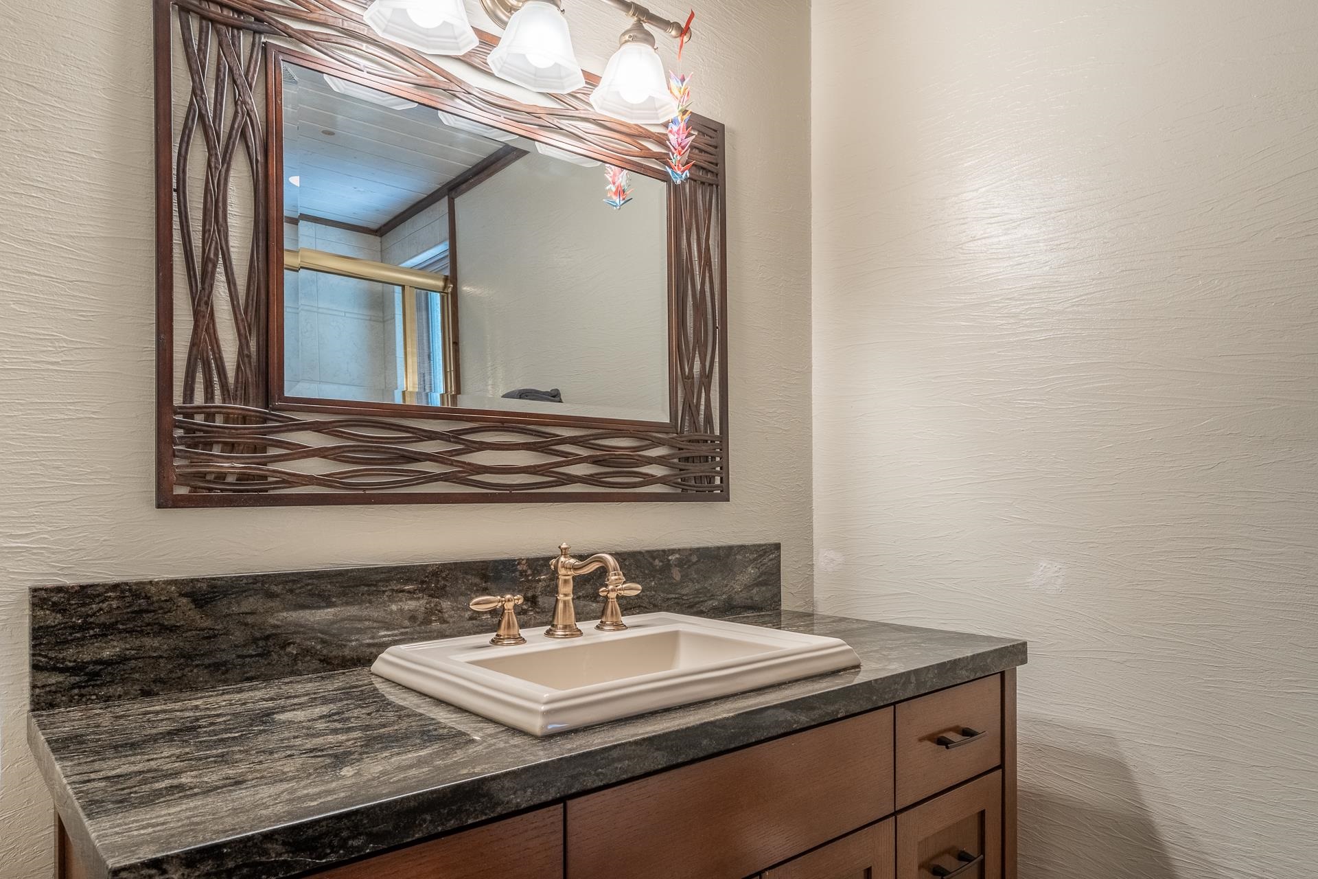 139 Ridgecrest Drive Mammoth Lakes, CA 93546 - Photo 44 of 65 Bathroom vanity featuring a dark stone countertop, an undermount sink, a bronze-finish faucet