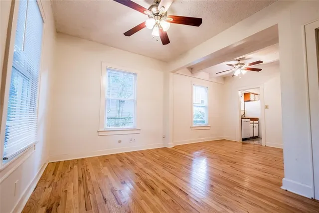 a view of empty room with wooden floor and fan