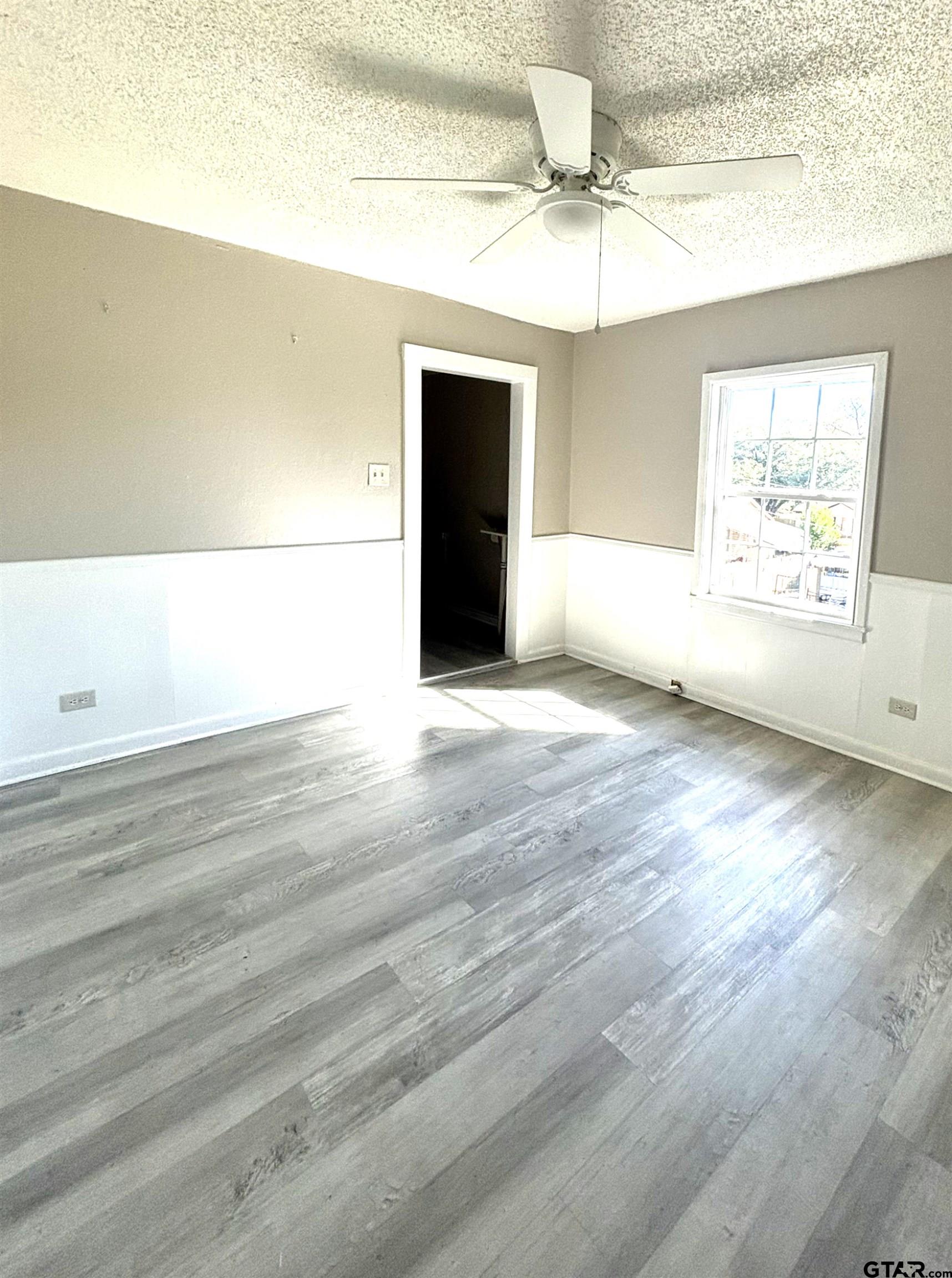 1511 Summit Avenue, Unit 3 Tyler, TX 75702 - Photo 8 of 8 en empty room with wooden floor chandelier and windows