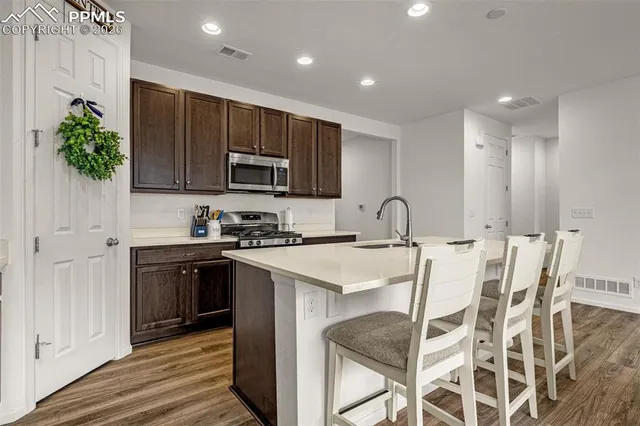 a kitchen with stainless steel appliances granite countertop a stove top oven a sink and a refrigerator