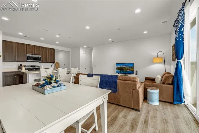 a kitchen with a refrigerator a sink dishwasher a stove and a dining table with wooden floor