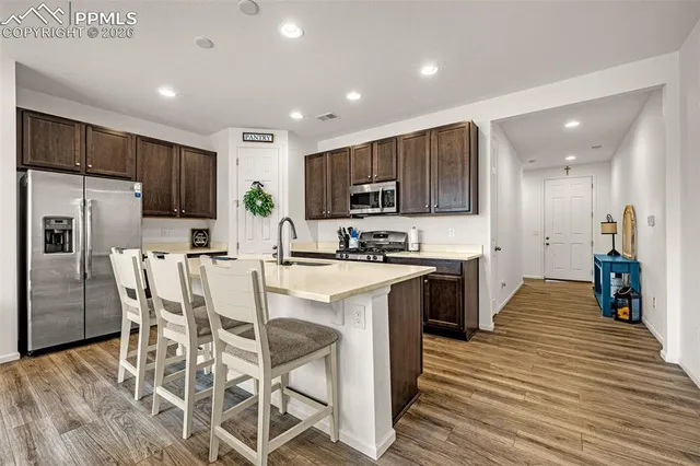 a kitchen with stainless steel appliances kitchen island granite countertop a refrigerator oven a sink a stove and a refrigerator with wooden floor