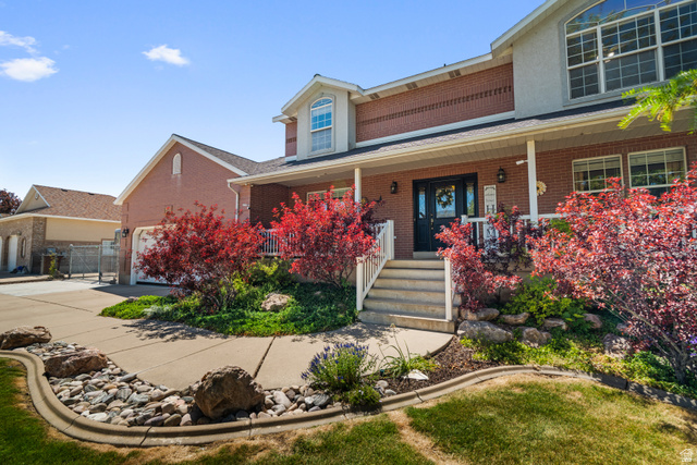 5727 South 3550th Street West Roy, UT 84067 - Photo 3 of 49 Brick exterior residence featuring a covered front porch with white railings, entry door, and multi-paned windows