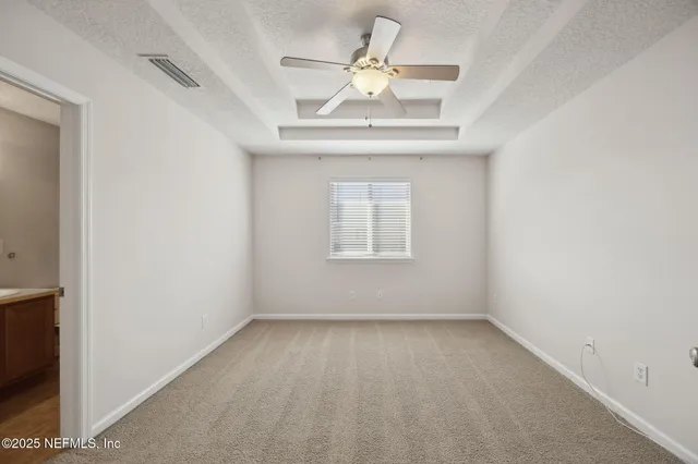 an empty room with a window and a fan