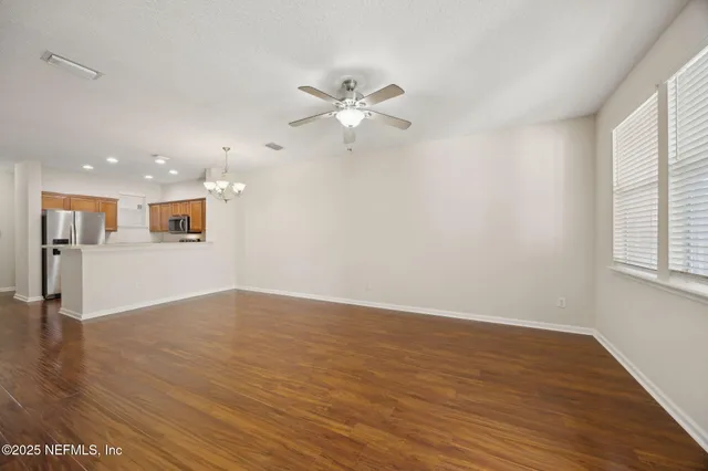 a view of an empty room with window and wooden floor
