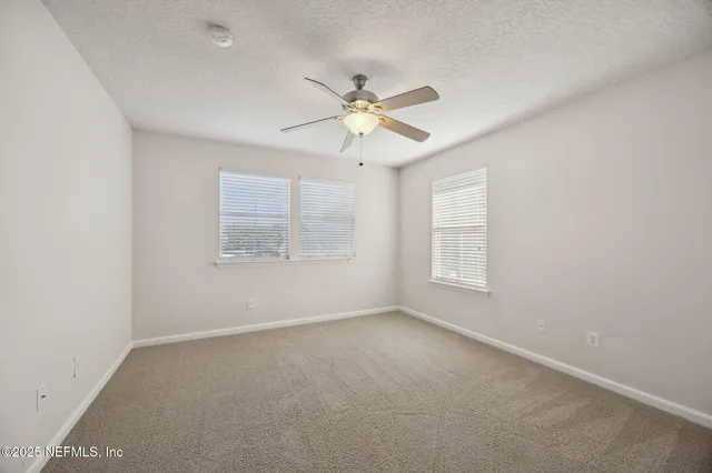 an empty room with a window and a ceiling fan