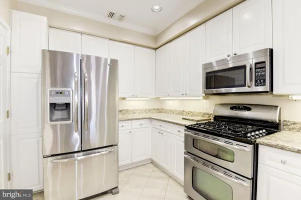 a kitchen with granite countertop a refrigerator stove and microwave