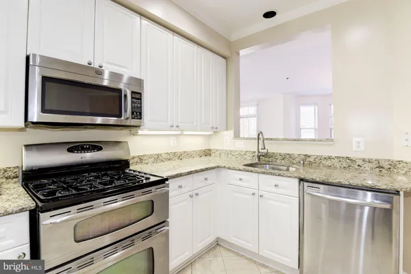 a kitchen with granite countertop a stove sink and microwave