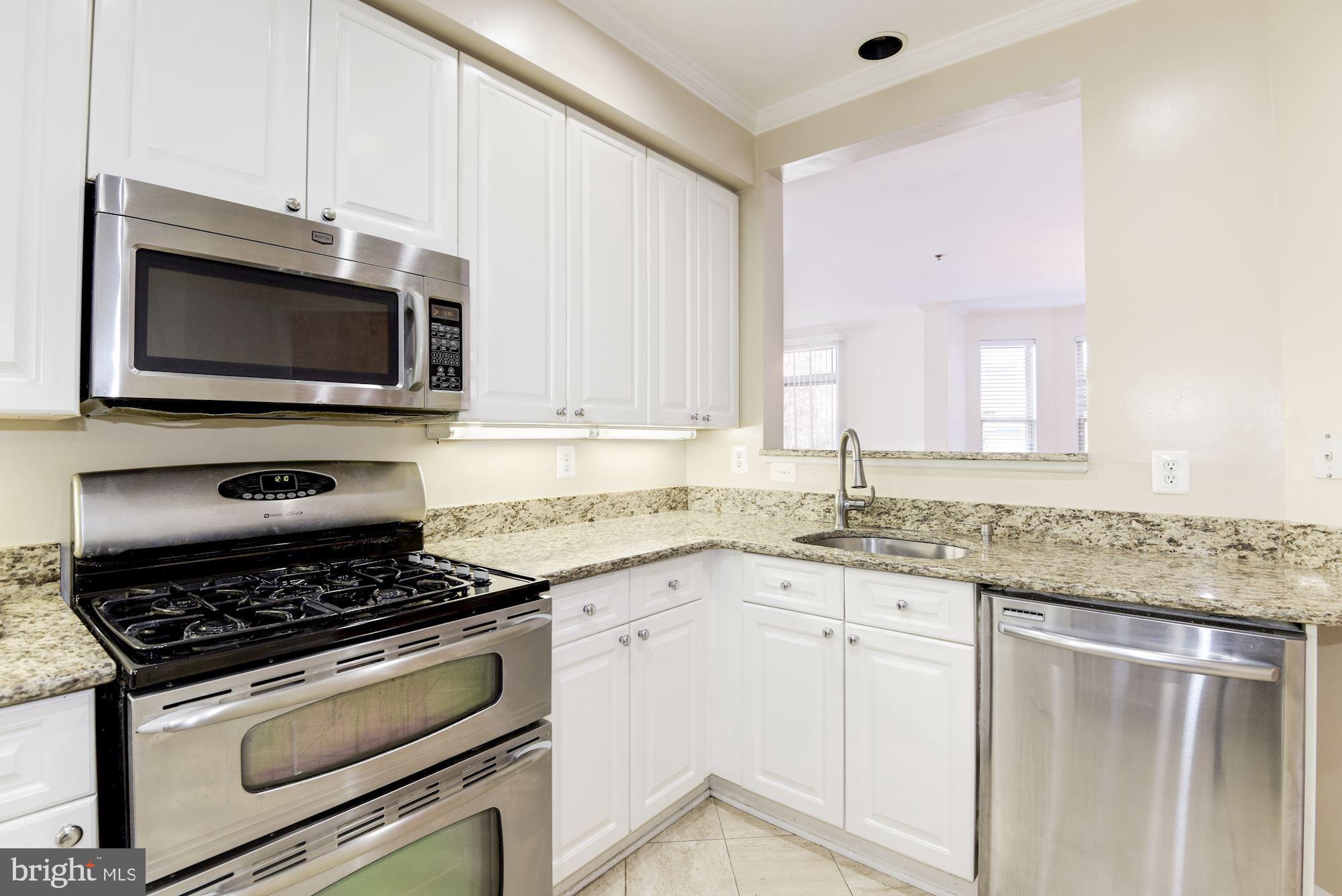 1860 Stratford Park Place, Unit 204 Reston, VA 20190 - Photo 17 of 41 a kitchen with granite countertop a stove sink and microwave