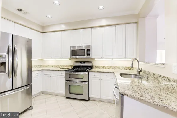 a kitchen with stainless steel appliances granite countertop a sink stove and refrigerator