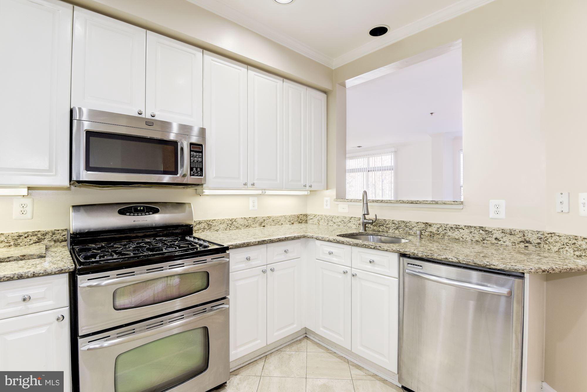 1860 Stratford Park Place, Unit 204 Reston, VA 20190 - Photo 19 of 41 a kitchen with granite countertop a stove sink and microwave