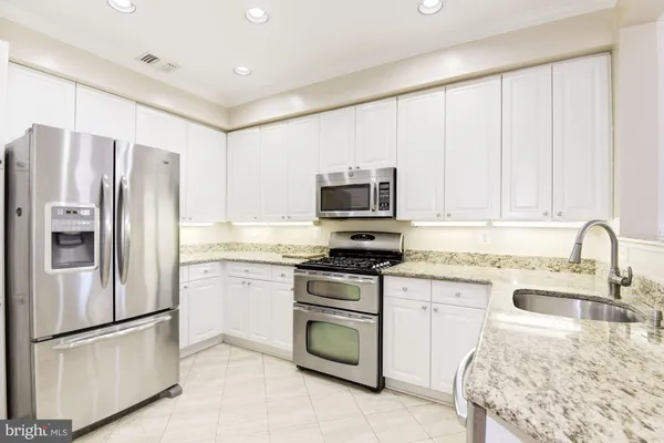 a kitchen with granite countertop white cabinets and stainless steel appliances