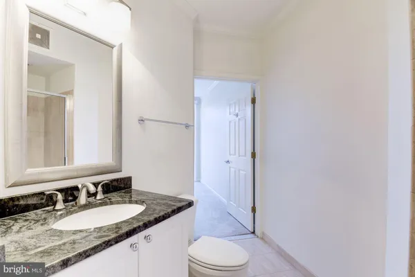 a bathroom with a granite countertop sink mirror vanity and toilet