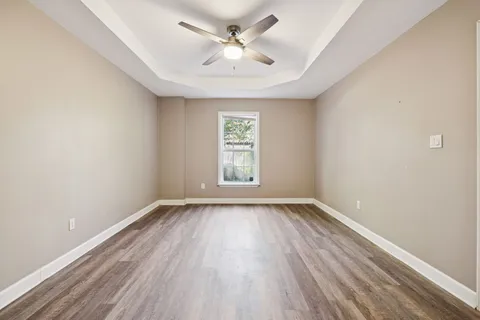 a view of an empty room with wooden floor and a window