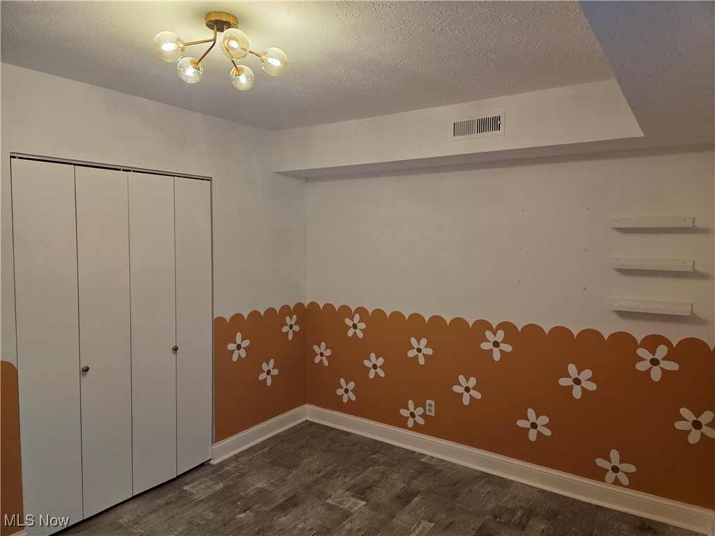 22958 Maple Ridge Road, Unit 205 North Olmsted, OH 44070 - Photo 20 of 28 Unfurnished bedroom featuring wood finished floors, a textured ceiling, a closet, and a chandelier