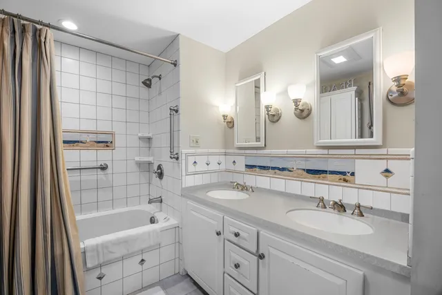 a bathroom with a sink double vanity granite tub shower and a mirror