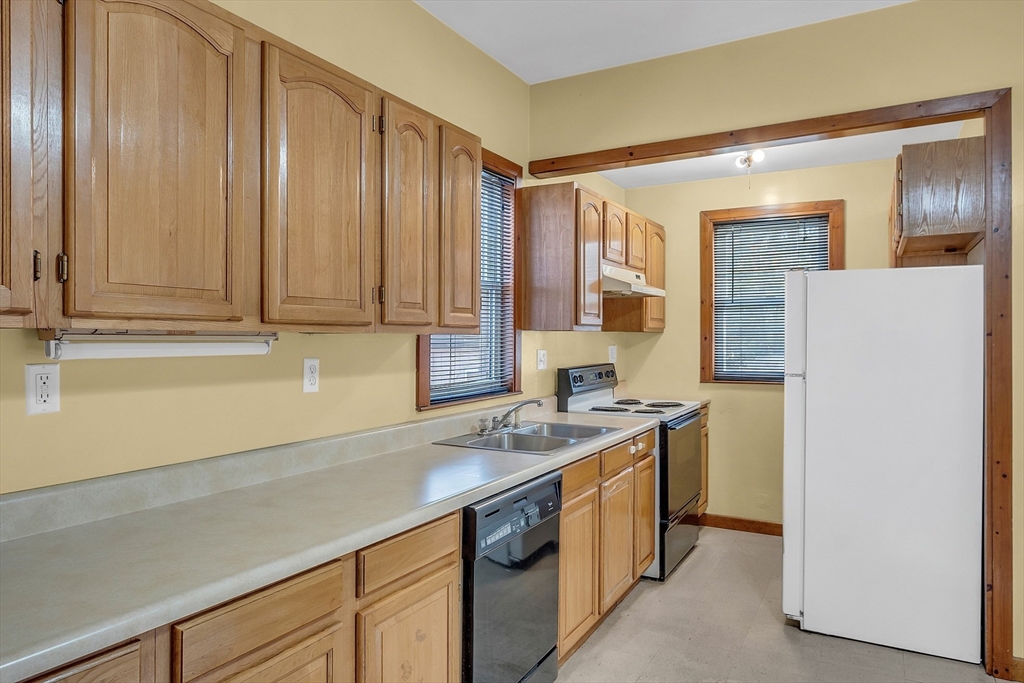 24 Lancaster Road Shirley, MA 01464 - Photo 23 of 35 a kitchen with stainless steel appliances granite countertop a sink a stove a refrigerator a washer and dryer with wooden cabinets