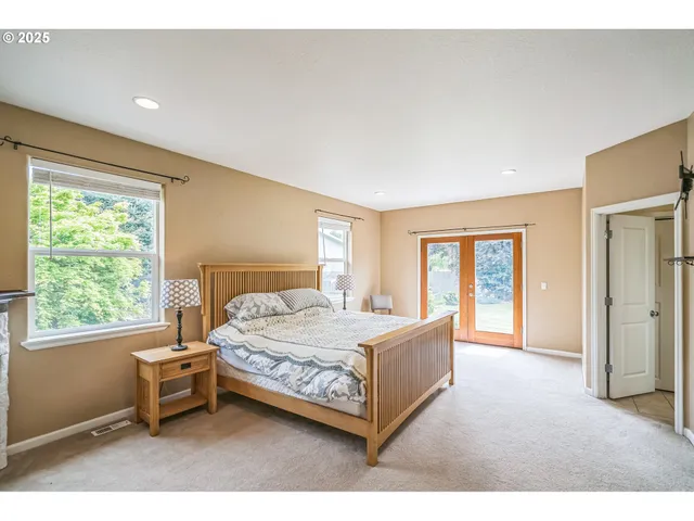 a bedroom with a bed and large windows