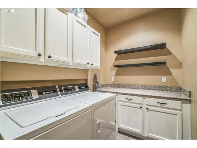 a kitchen with granite countertop a stove a sink and white cabinets