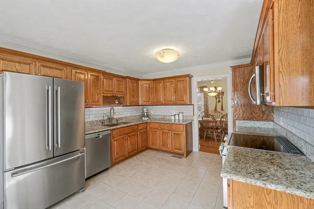 a kitchen with stainless steel appliances granite countertop a refrigerator a stove and a sink with large window