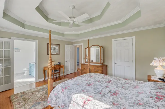 a bedroom with a bed a chandelier and mirror