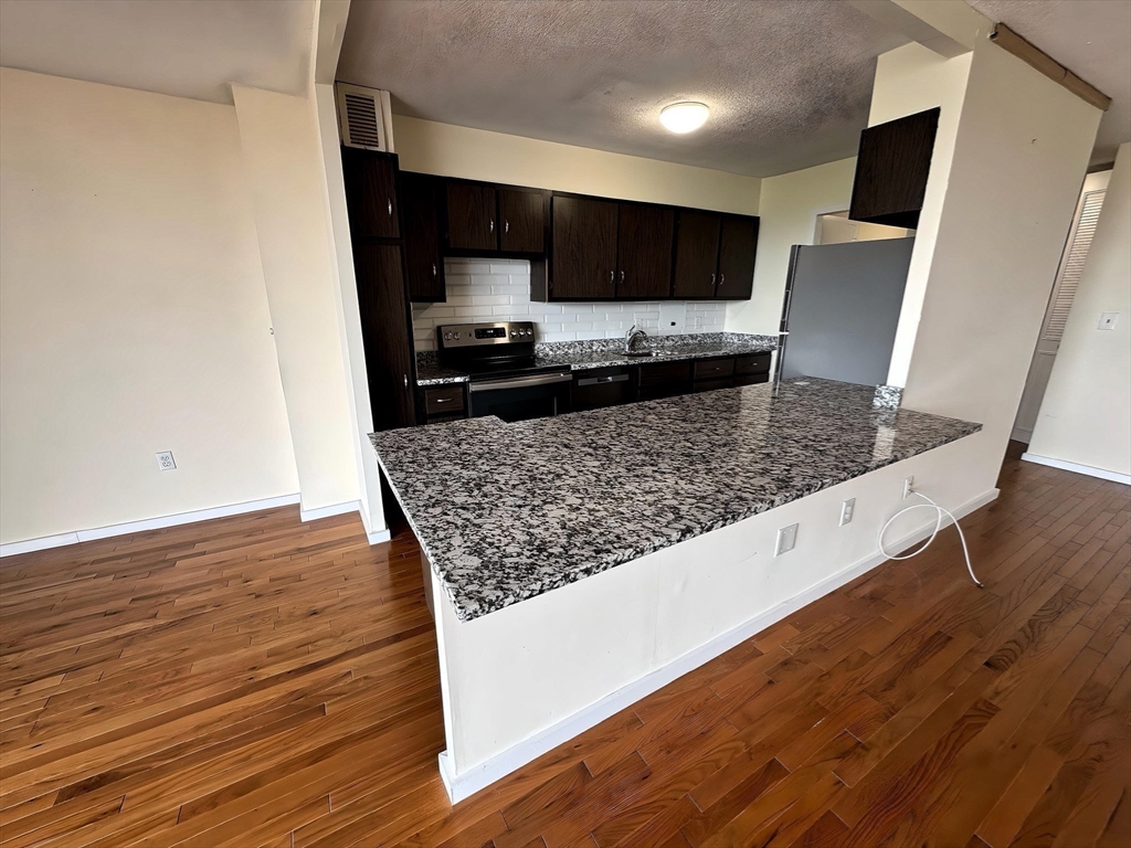 60 Longwood Avenue, Unit 802 Brookline, MA 02446 - Photo 5 of 16 a kitchen with stainless steel appliances granite countertop a sink stove and wooden floor