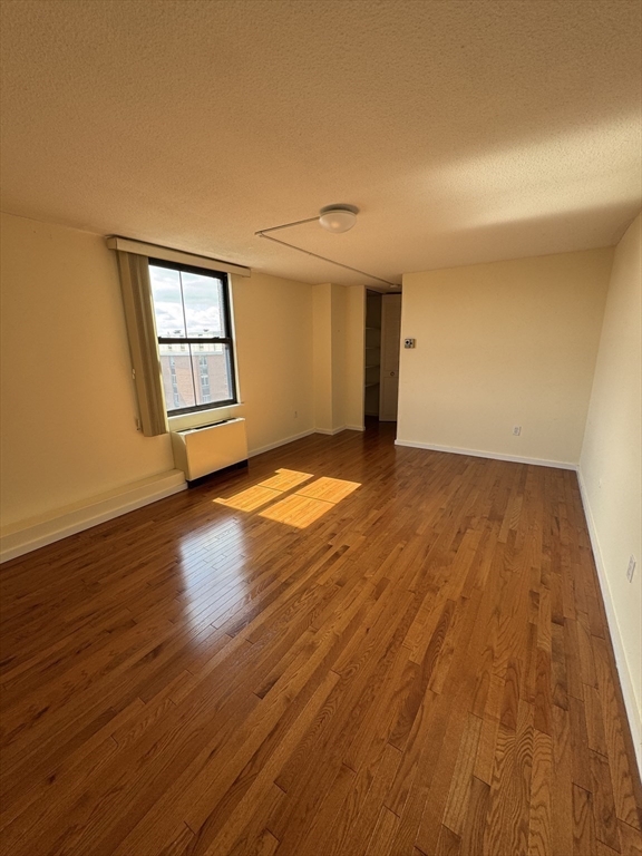60 Longwood Avenue, Unit 802 Brookline, MA 02446 - Photo 9 of 16 a view of an empty room with wooden floor and a window