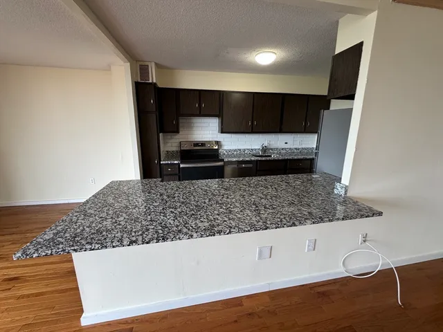 a kitchen with stainless steel appliances kitchen island granite countertop a sink stove and refrigerator