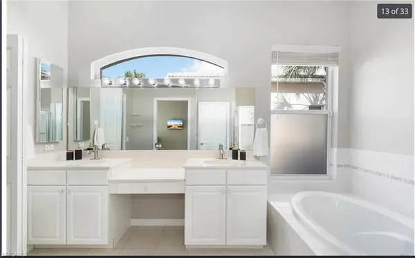 a bathroom with a double vanity sink mirror and bathtub