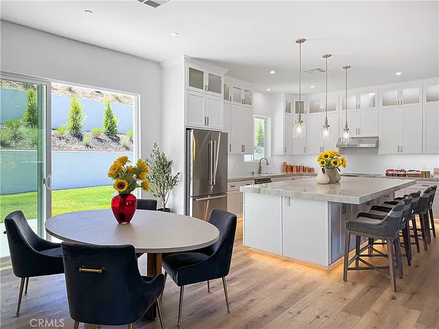 a kitchen with stainless steel appliances a dining table chairs and white cabinets