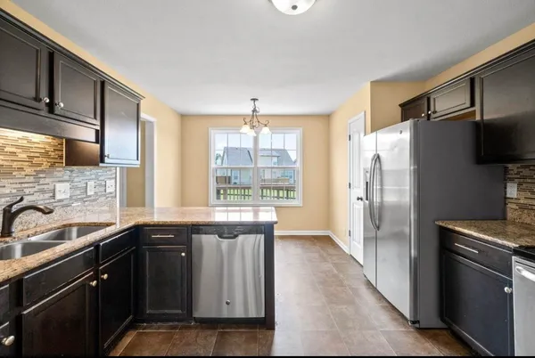 a kitchen with granite countertop a refrigerator and a sink