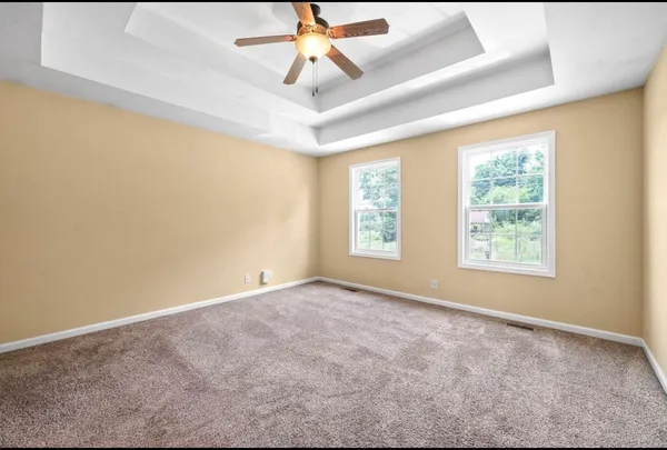 an empty room with windows and fan