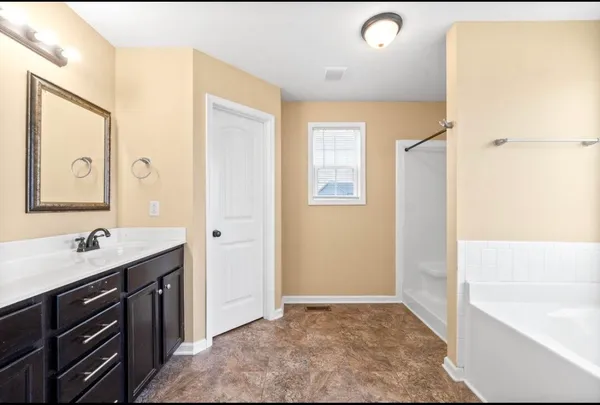 a bathroom with a tub sink and mirror