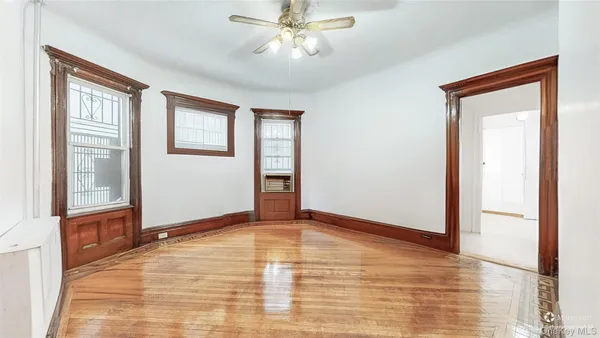 a view of an empty room with window and chandelier fan