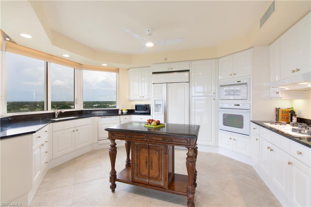 6597 Nicholas Boulevard, Unit 1006 Naples, FL 34108 - Photo 2 of 6 a kitchen with stainless steel appliances kitchen island granite countertop a table chairs sink and cabinets