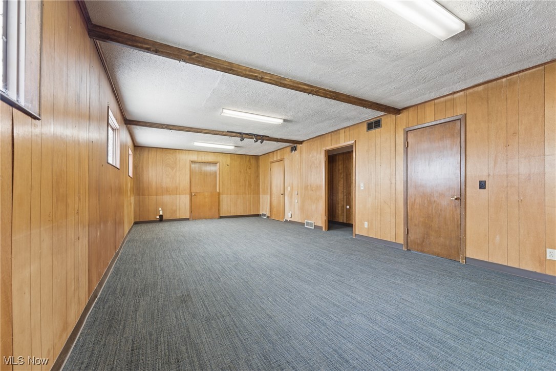 1817 Fulton Road Northwest Canton, OH 44709 - Photo 10 of 25 Bonus room with beam ceiling, a textured ceiling, wooden walls, and dark carpet