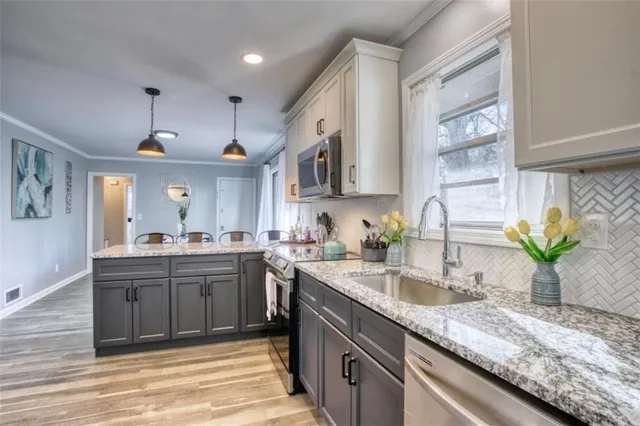 a kitchen with kitchen island granite countertop a sink stainless steel appliances and cabinets