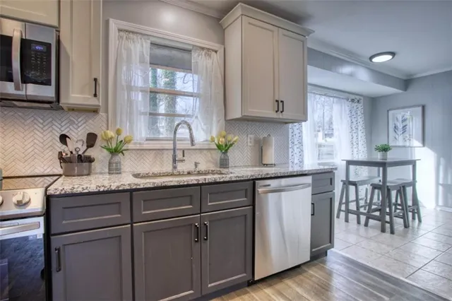 a kitchen with granite countertop a sink stainless steel appliances and cabinets