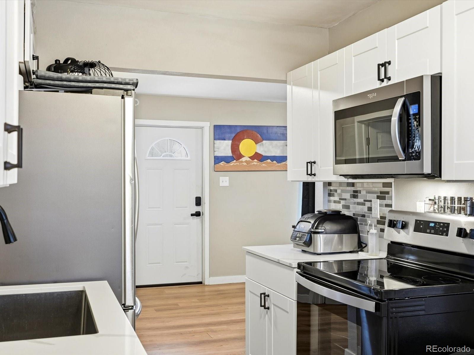 1883 South Perry Way Denver, CO 80219 - Photo 11 of 36 a kitchen with stainless steel appliances granite countertop a sink stove and refrigerator