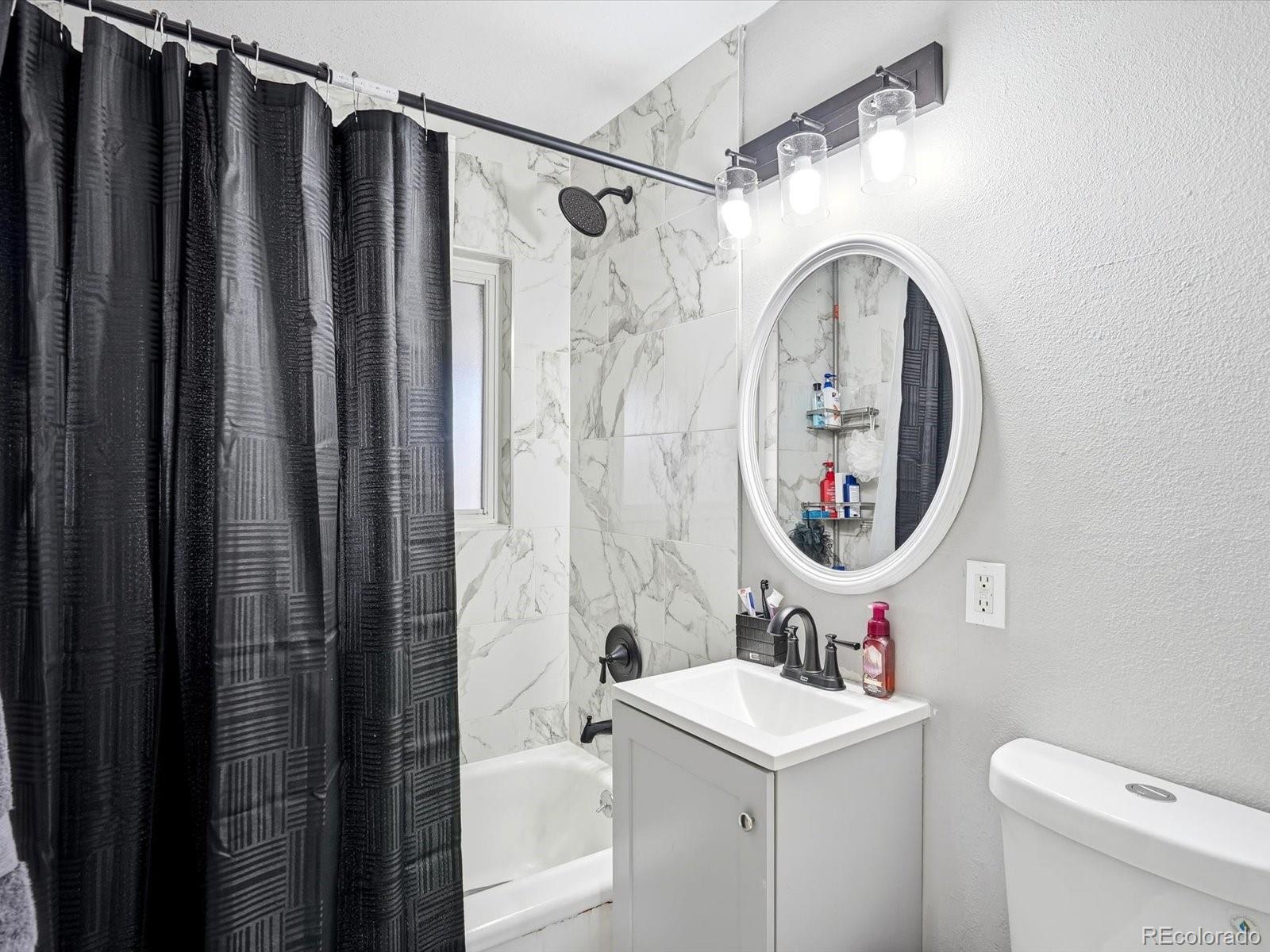 1883 South Perry Way Denver, CO 80219 - Photo 25 of 36 a bathroom with a sink a toilet and a mirror