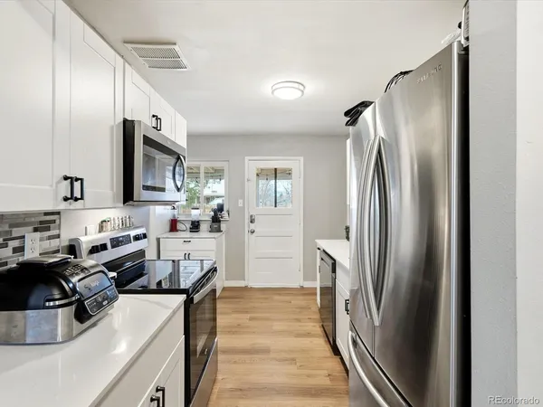 a kitchen with stainless steel appliances granite countertop a refrigerator a sink a stove and a refrigerator with wooden floor